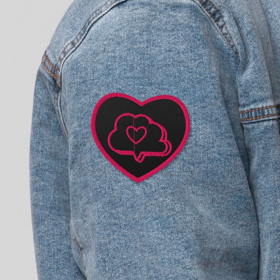 Fabric patch that is a black heart shape with pink border. Inside the heart is a pink thought bubble with a heart in it.